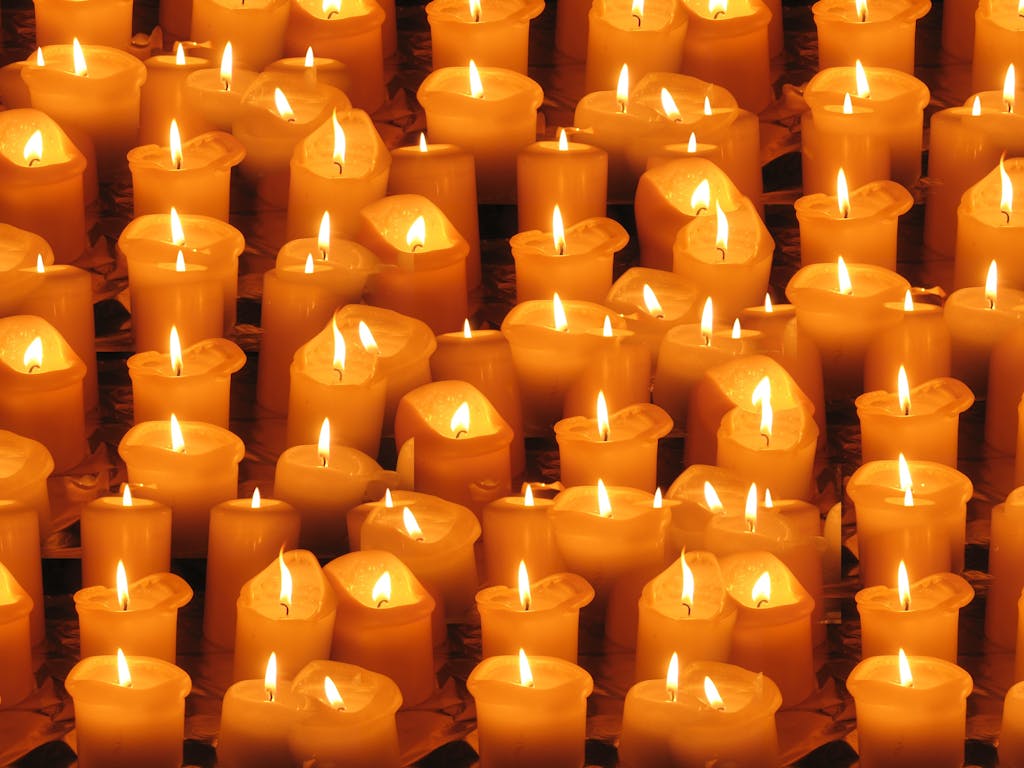 A warm and serene display of numerous burning candles arranged closely together.